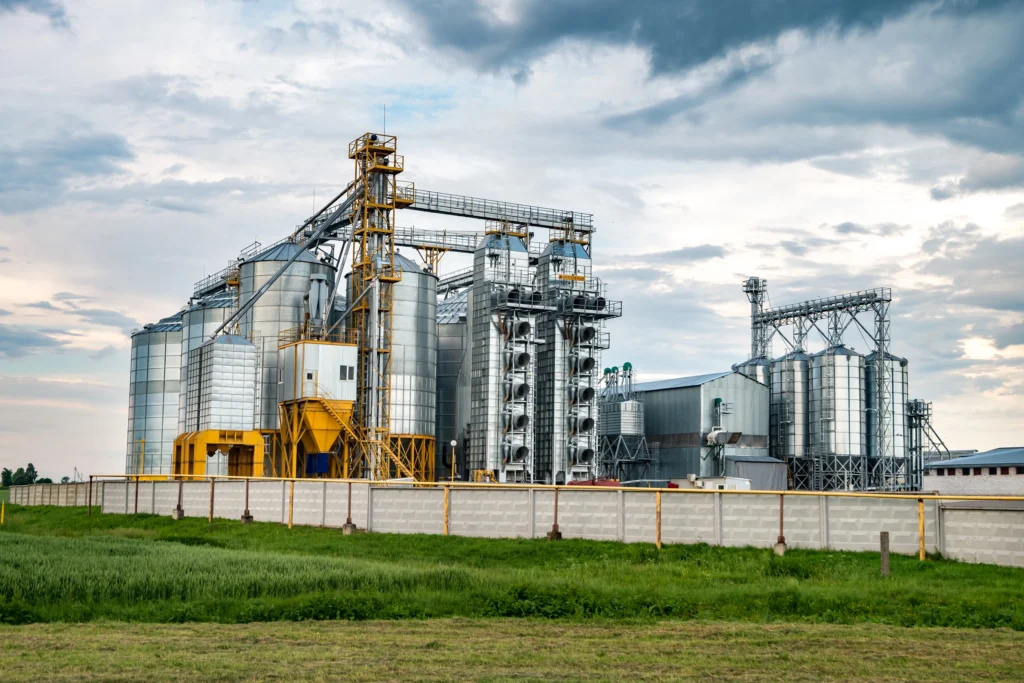 Usina sucroalcooleira com silos metálicos e estruturas industriais.