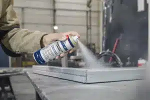 Funcionário na indústria usando desingripante spray